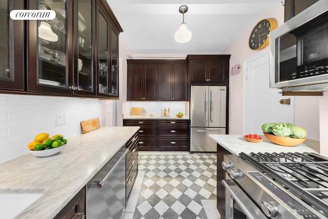 kitchen with decorative backsplash, decorative light fixtures, stainless steel appliances, dark brown cabinets, and light floors