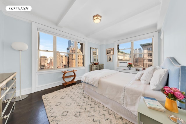 bedroom with a view of city, wood finished floors, visible vents, and baseboards