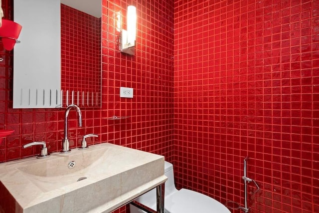 bathroom with toilet, backsplash, vanity, and tile walls