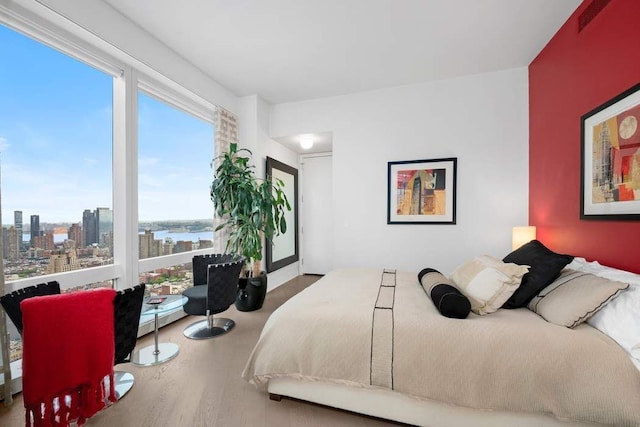 bedroom featuring wood finished floors, visible vents, and a city view