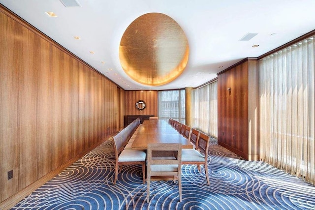 unfurnished dining area featuring wood walls and a tray ceiling