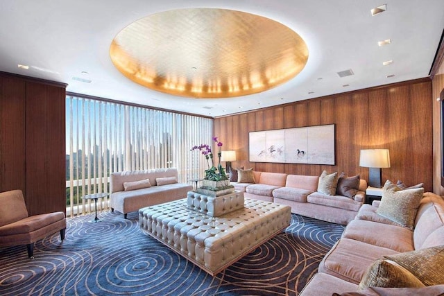 living area with a raised ceiling, visible vents, and wooden walls