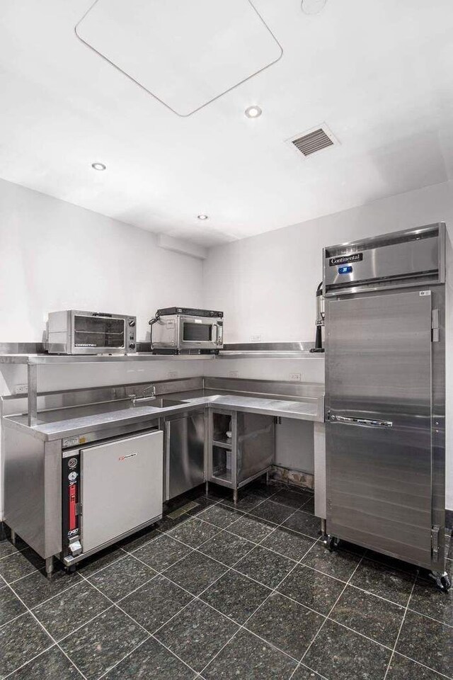 kitchen with granite tiled floors, appliances with stainless steel finishes, recessed lighting, and a sink