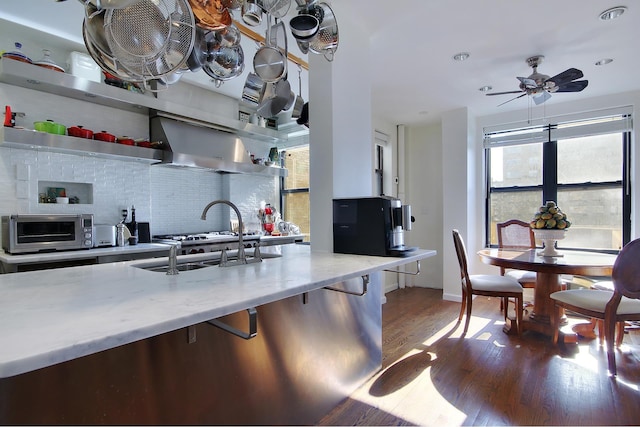 kitchen with a toaster, wood finished floors, a ceiling fan, backsplash, and light stone countertops