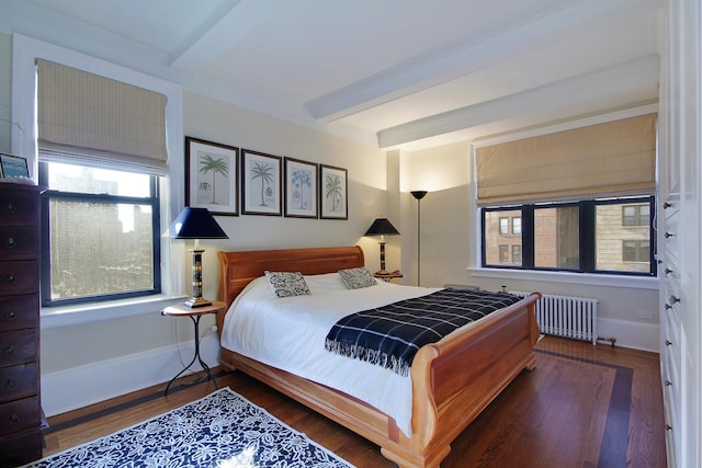 bedroom featuring dark wood-style floors, beam ceiling, baseboards, and radiator heating unit