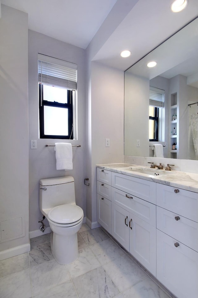 full bathroom featuring a healthy amount of sunlight, toilet, vanity, and baseboards