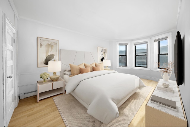 bedroom featuring a baseboard heating unit and light wood-type flooring