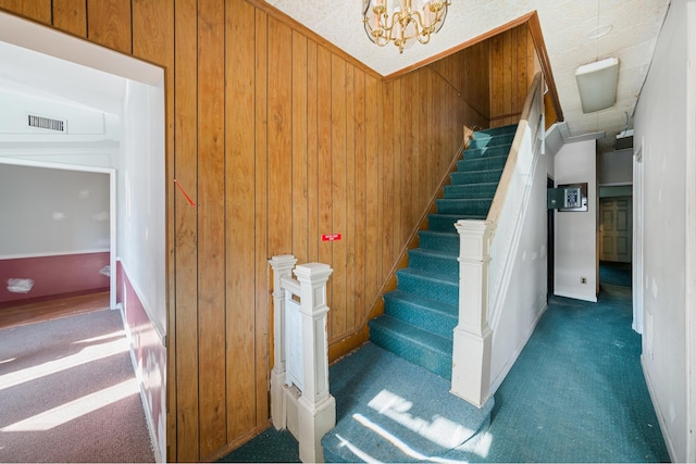 stairs featuring carpet floors, a chandelier, visible vents, and wood walls