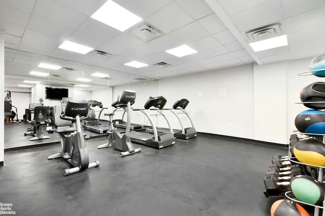 workout area with baseboards, visible vents, and a drop ceiling