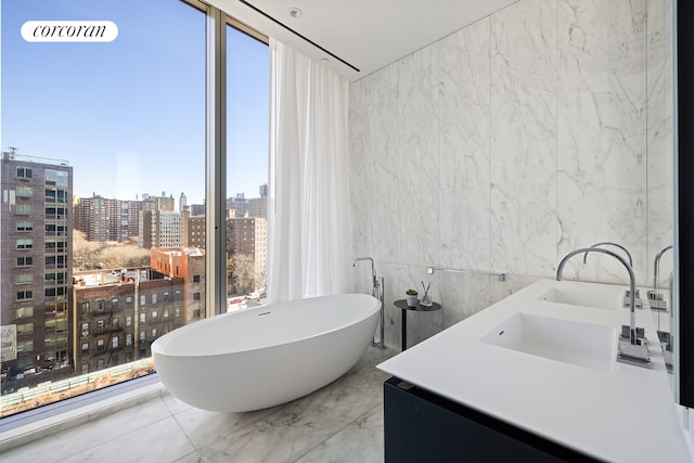 520 W 28th St Unit 29, New York City, NY 10001 - bathroom with a freestanding bath, marble tiled flooring, a view of city, and double vanity