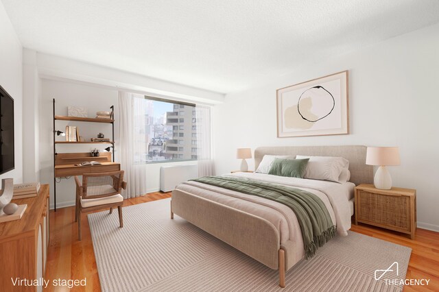 170 Park Row Unit 7C, New York City, NY 10038 - bedroom featuring light wood finished floors, radiator heating unit, and baseboards