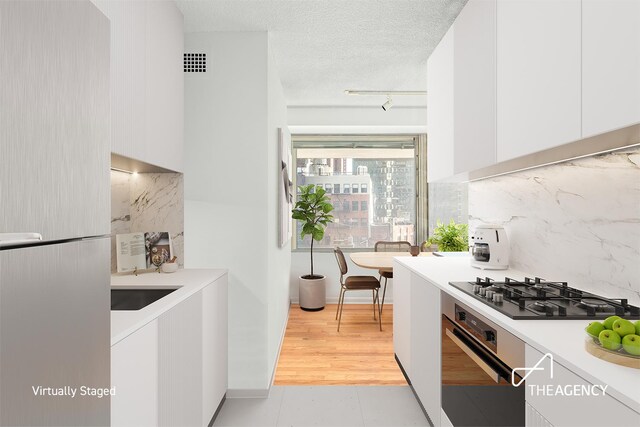170 Park Row Unit 7C, New York City, NY 10038 - kitchen featuring oven, gas cooktop, white cabinets, and a textured ceiling
