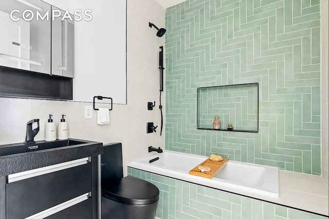 bathroom with tile walls, tiled shower / bath, and vanity