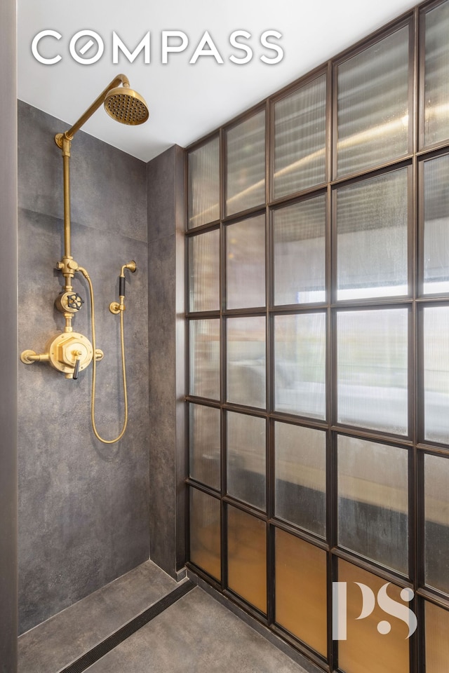 bathroom with tiled shower and concrete floors