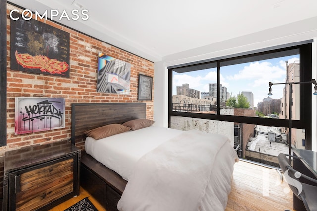 bedroom with access to exterior, a view of city, and wood finished floors