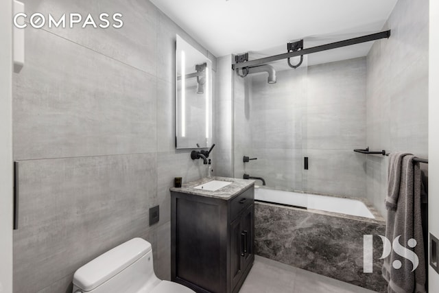 full bath featuring tile patterned floors, toilet, combined bath / shower with glass door, tile walls, and vanity