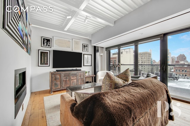 bedroom featuring baseboards, a glass covered fireplace, hardwood / wood-style floors, access to outside, and french doors