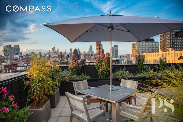 view of patio featuring outdoor dining area, a view of city, and a balcony