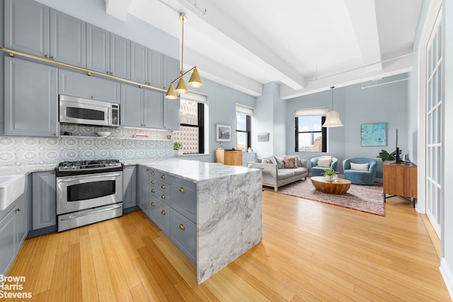 kitchen featuring a peninsula, gas stove, beam ceiling, and gray cabinetry