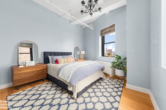 bedroom with an inviting chandelier, baseboards, and wood finished floors