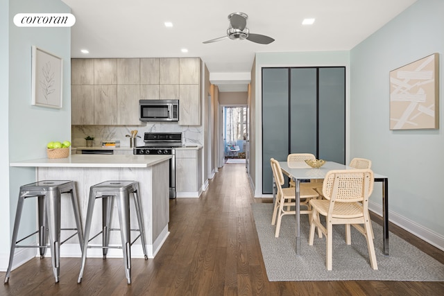 kitchen with a breakfast bar area, stainless steel appliances, dark wood-type flooring, light countertops, and modern cabinets