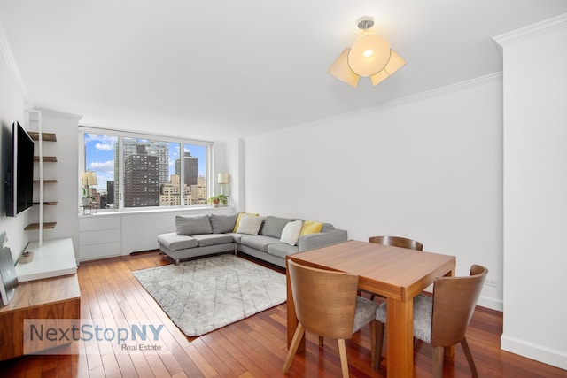 living area featuring crown molding, wood-type flooring, baseboards, and a city view