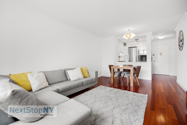 living room with dark wood finished floors, baseboards, and ornamental molding