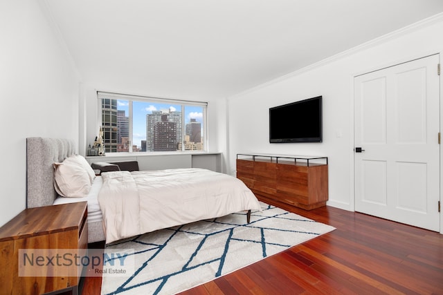 bedroom with ornamental molding and dark wood-style flooring