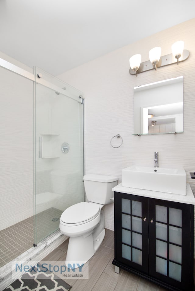 245 E 54th St Unit 19K, New York City, NY 10022 - bathroom with toilet, vanity, a stall shower, and tile walls