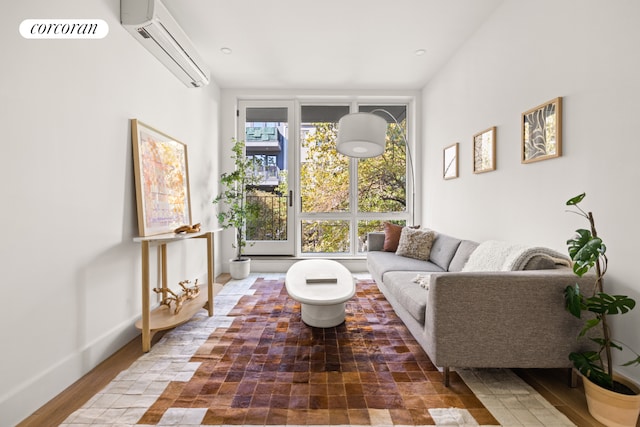 living room with a wall mounted air conditioner, baseboards, and wood finished floors