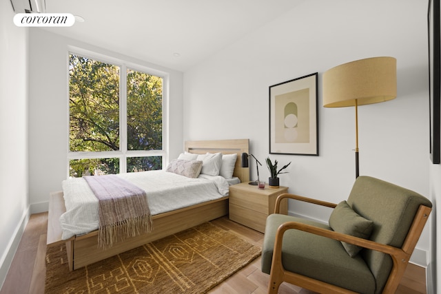 bedroom featuring lofted ceiling, baseboards, and wood finished floors