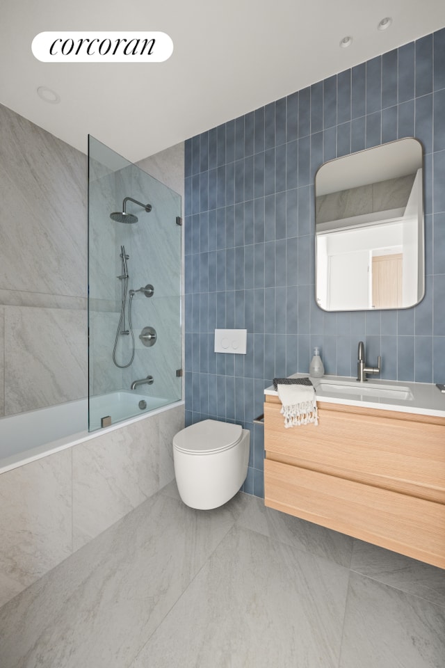 bathroom with tiled shower / bath combo, tile walls, toilet, and vanity