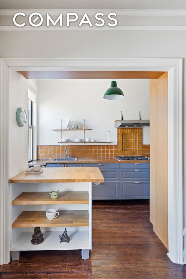 kitchen featuring dark wood-style flooring, stainless steel gas stovetop, wooden counters, decorative backsplash, and a sink