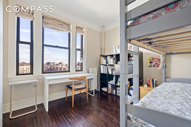 bedroom with radiator heating unit, baseboards, and hardwood / wood-style floors