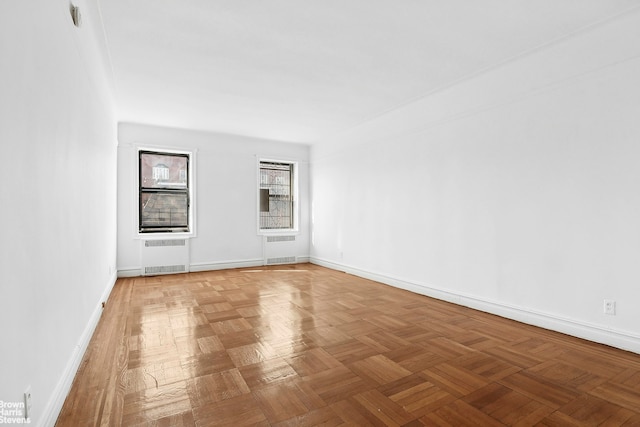 empty room with radiator, visible vents, and baseboards