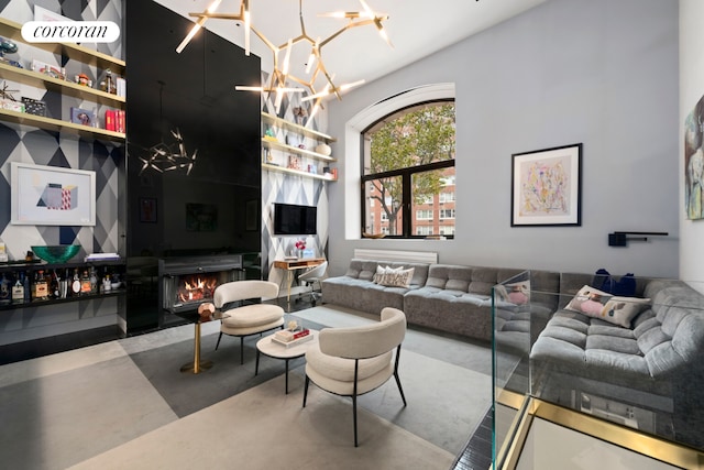 living room featuring a notable chandelier, a fireplace, a towering ceiling, and finished concrete floors