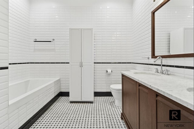 full bathroom featuring a tub to relax in, tile walls, double vanity, toilet, and a sink