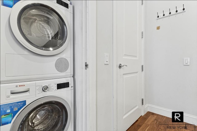 washroom with stacked washer and dryer, baseboards, laundry area, and dark wood-style flooring