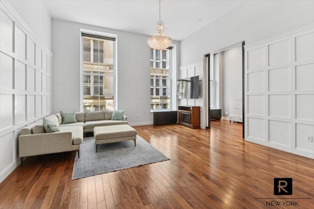 living area with hardwood / wood-style flooring, baseboards, and a chandelier