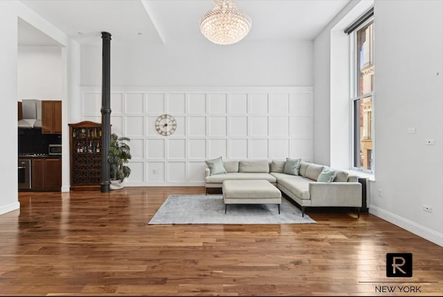 living area featuring dark wood-type flooring, a chandelier, and baseboards