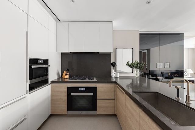 kitchen featuring wall oven, white cabinets, a sink, modern cabinets, and oven