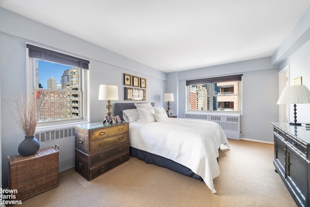 bedroom featuring a view of city, radiator heating unit, light carpet, and baseboards