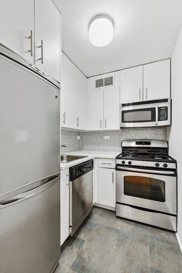 kitchen featuring decorative backsplash, stainless steel appliances, light countertops, a sink, and visible vents