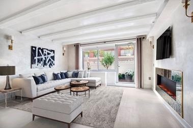 living room with beamed ceiling and a glass covered fireplace