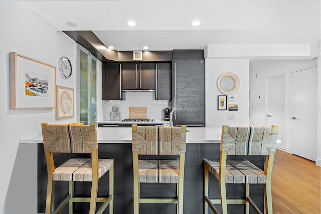 kitchen featuring light countertops, a breakfast bar, light wood-type flooring, and visible vents