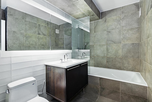 bathroom with tiled shower / bath, tile walls, toilet, and vanity