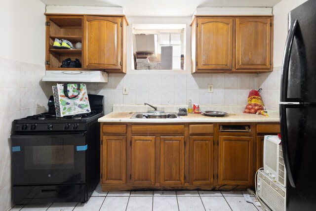 kitchen with a sink, exhaust hood, light countertops, brown cabinets, and black appliances