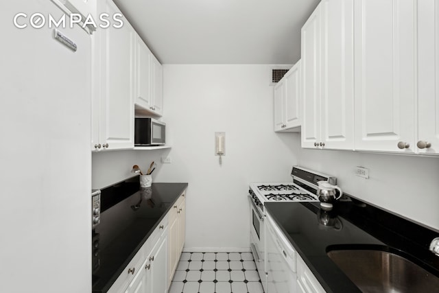 kitchen with white appliances, white cabinetry, a sink, and visible vents