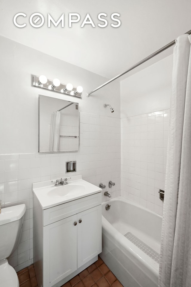 bathroom with toilet, tile patterned flooring, shower / bathtub combination with curtain, vanity, and tile walls