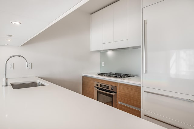 kitchen with light countertops, appliances with stainless steel finishes, white cabinetry, a sink, and modern cabinets